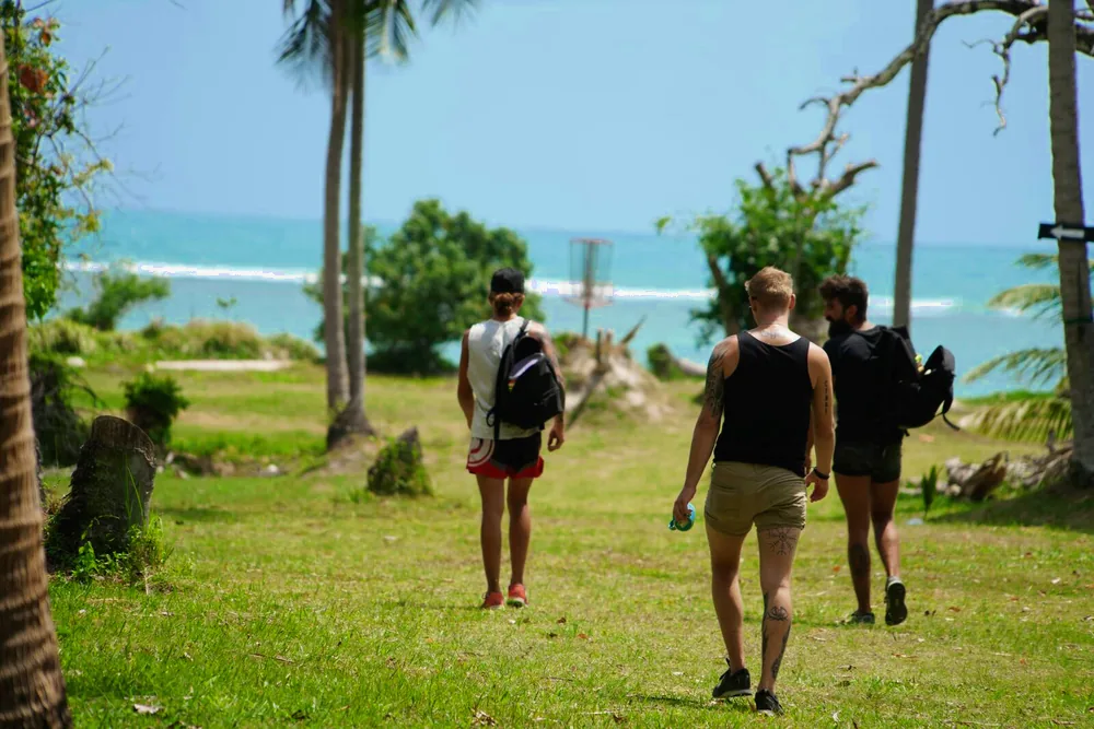 Three players walk the fairway toward the sea