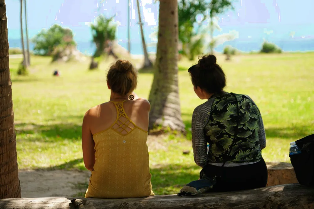Two visitors sit in the shade looking out over the course