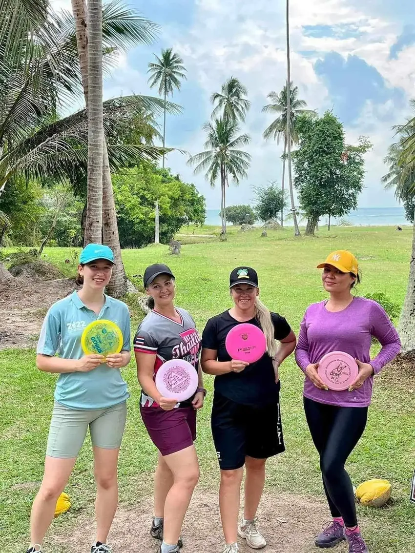 Four players hold up their discs on the fairway