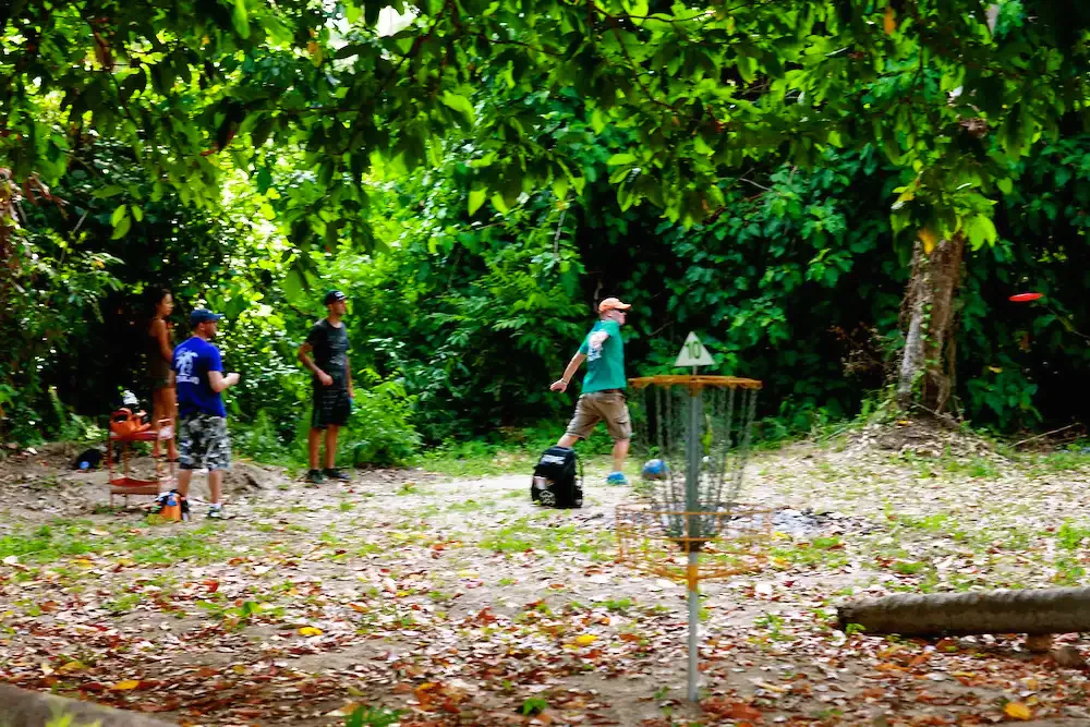 Players throw toward a basket in a jungle clearing