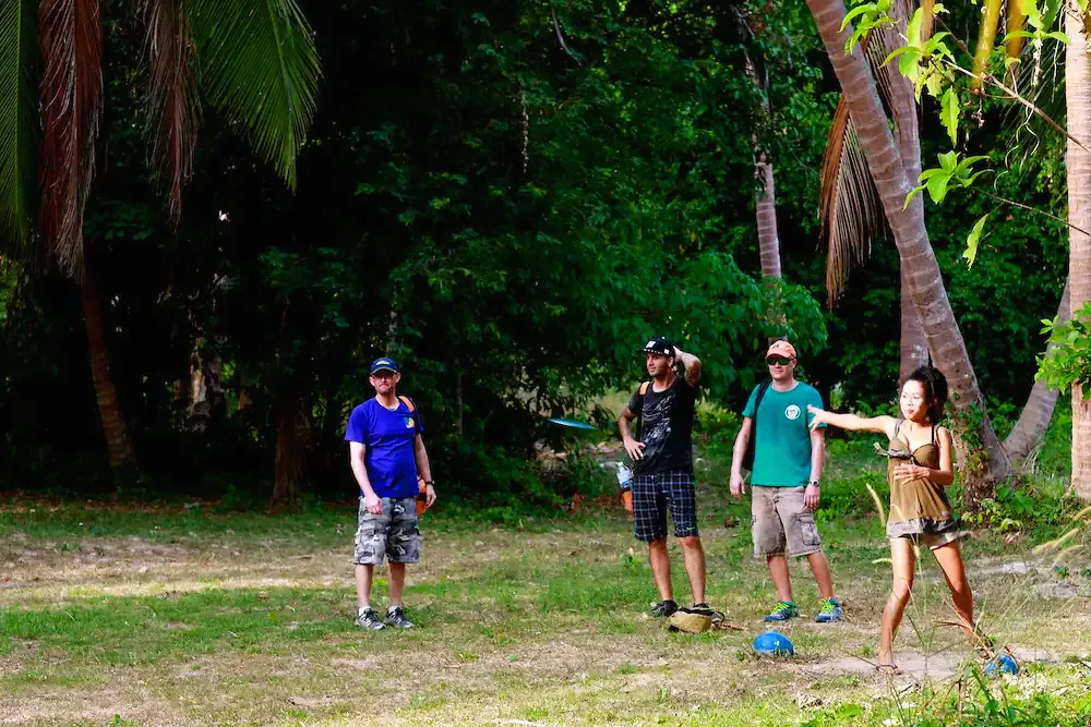 Four players on a jungle fairway, one throwing