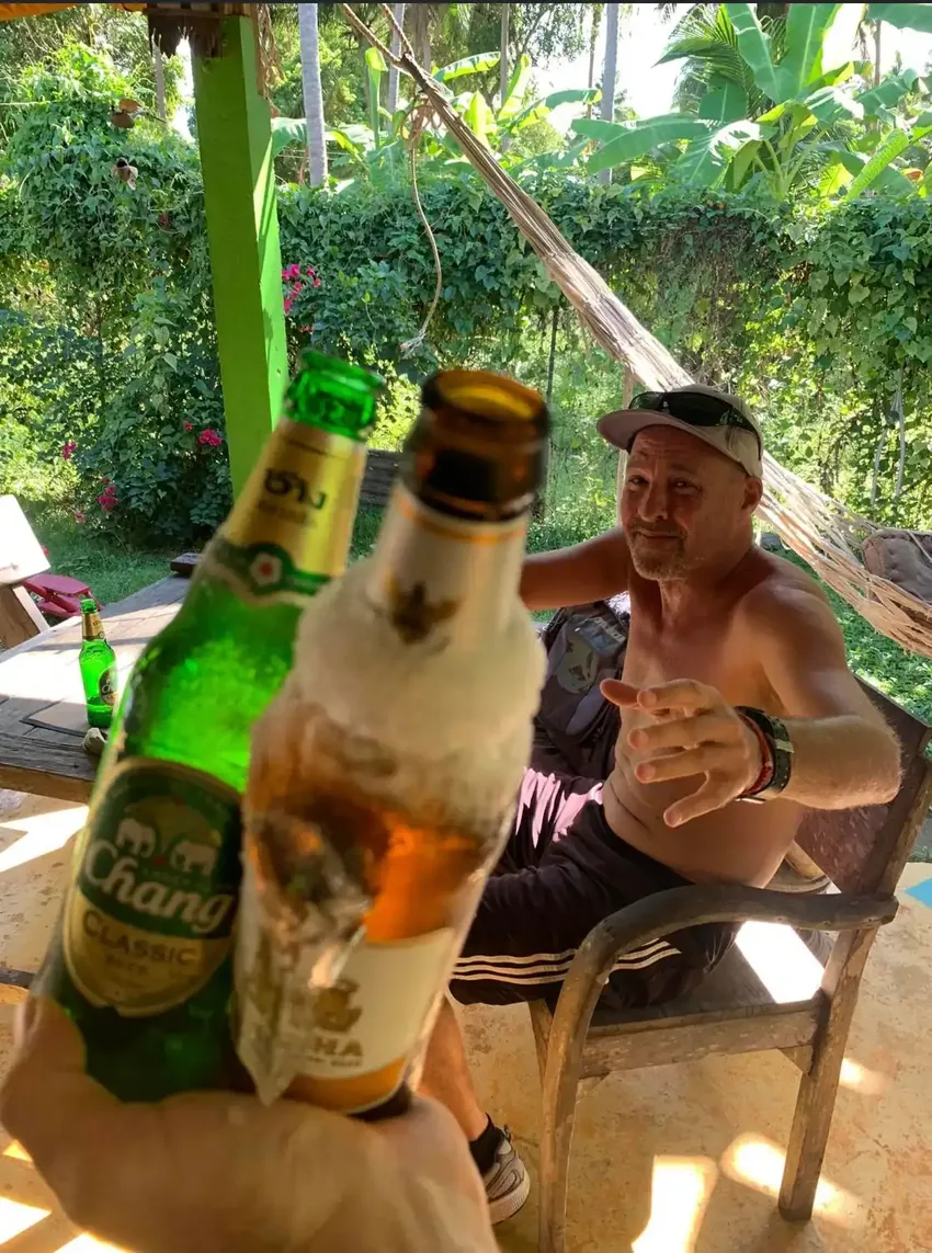 A visitor raises two cold drinks in the garden