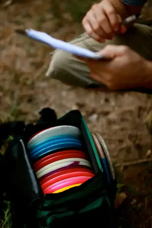 A scorecard being filled in over a bag of discs