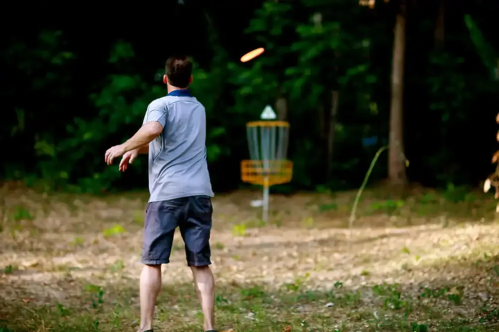 A player putts toward a basket in the jungle