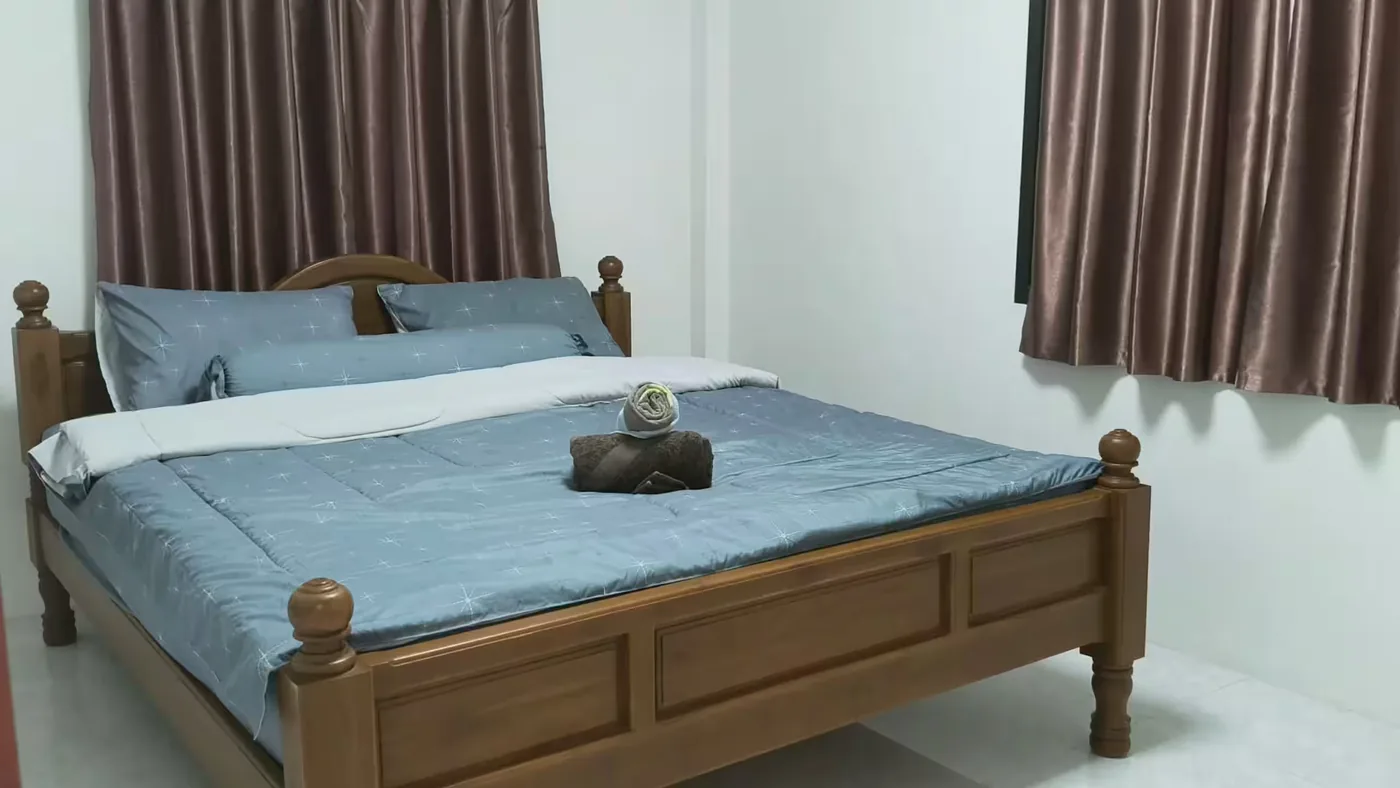 A guesthouse bedroom with a wooden double bed and blue linen